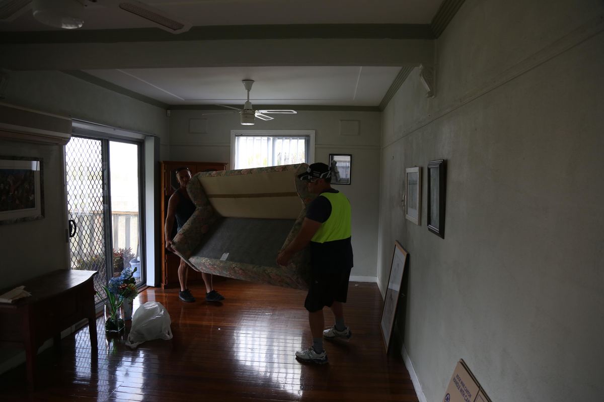 Two movers carrying a couch out of a house
